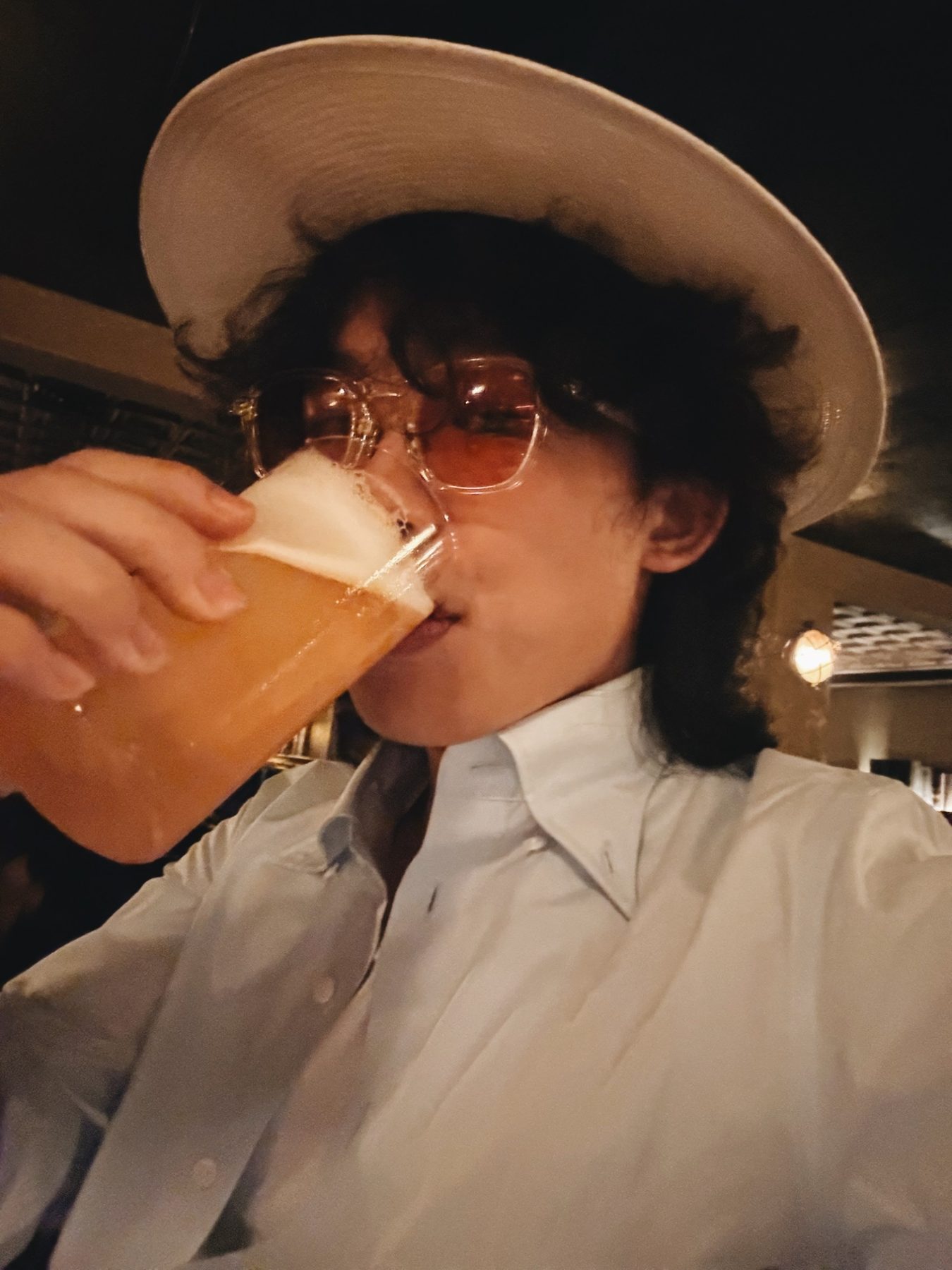 Alan Yang en chemise blanche, chapeau à large bord et lunettes teintées